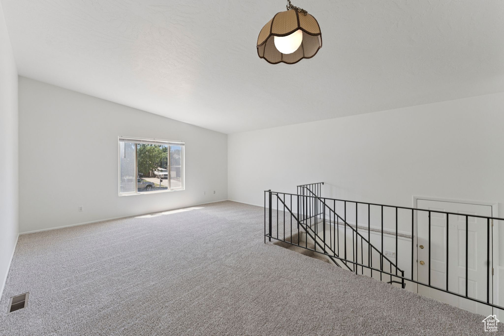 Unfurnished room featuring carpet floors and vaulted ceiling