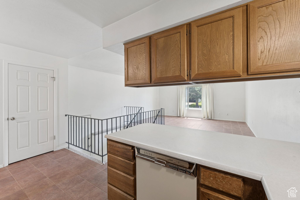 Kitchen with dishwasher, light countertops, brown cabinetry, and light tile patterned flooring