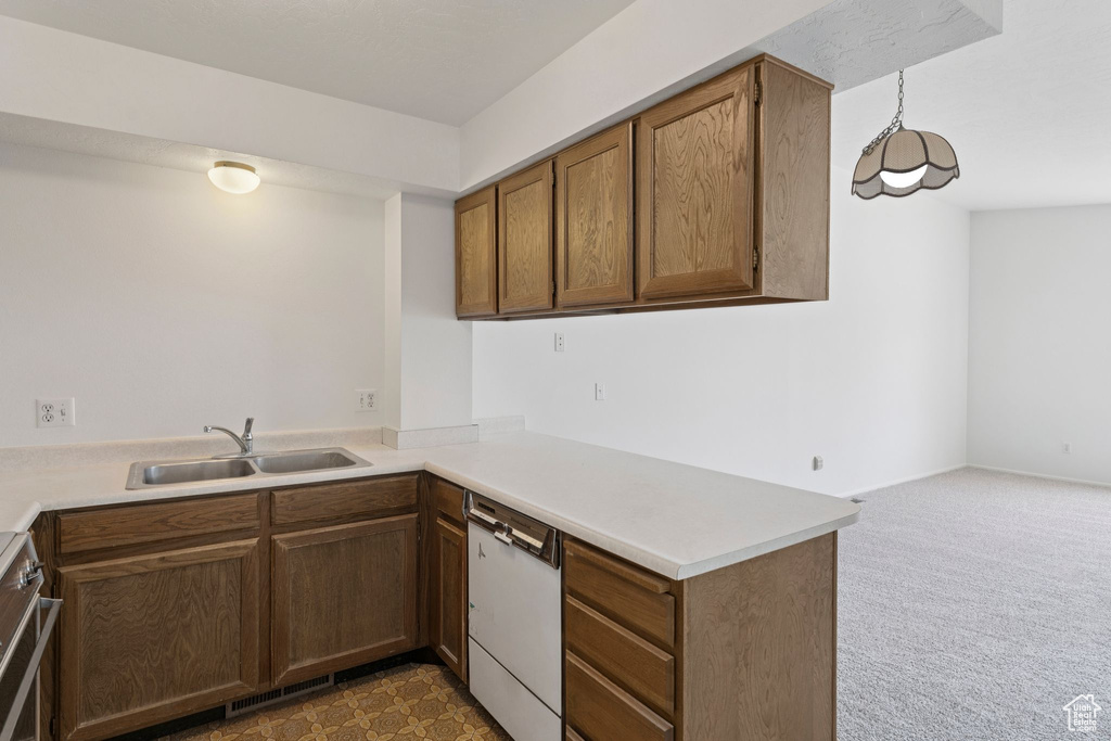 Kitchen with dishwasher, light countertops, carpet floors, a peninsula, and stainless steel range