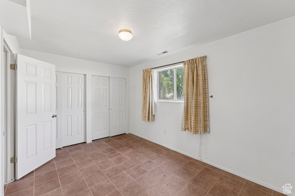 Unfurnished bedroom with multiple closets and baseboards