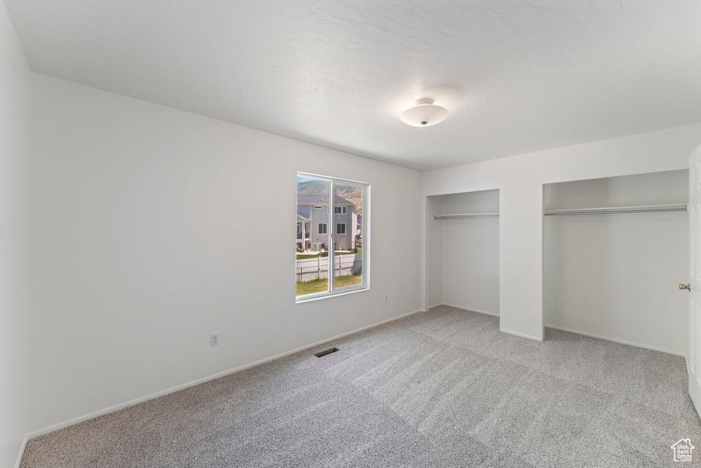 Unfurnished bedroom featuring multiple closets and carpet