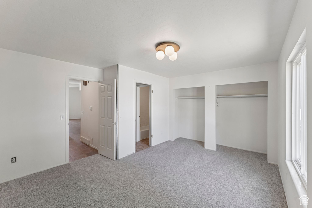 Unfurnished bedroom with carpet floors and two closets