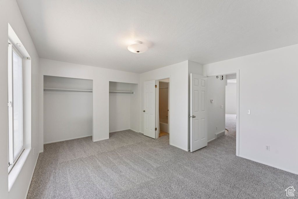 Unfurnished bedroom with two closets, carpet floors, and multiple windows