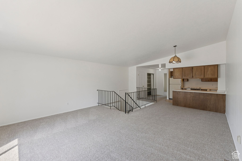 Unfurnished living room featuring vaulted ceiling and light carpet