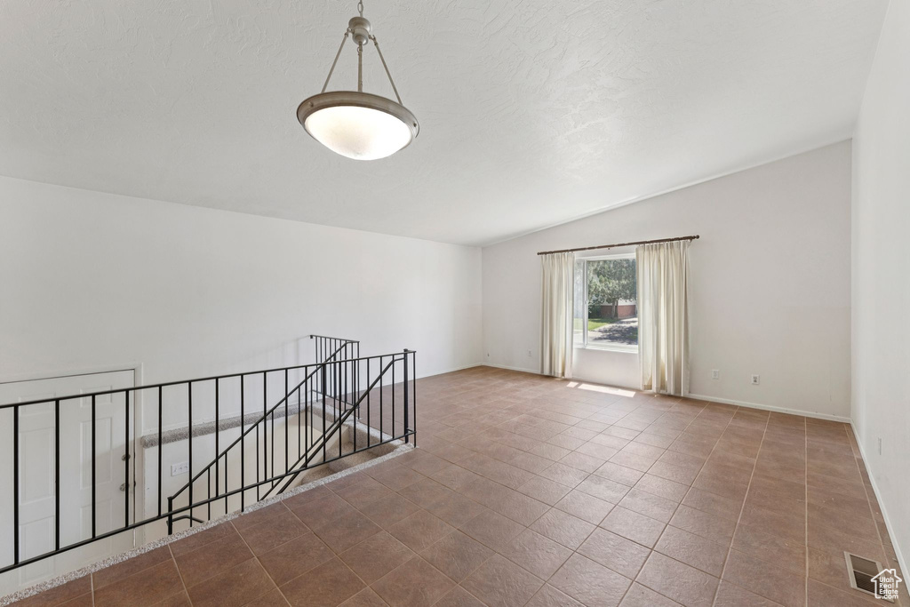Unfurnished room featuring vaulted ceiling and tile patterned flooring