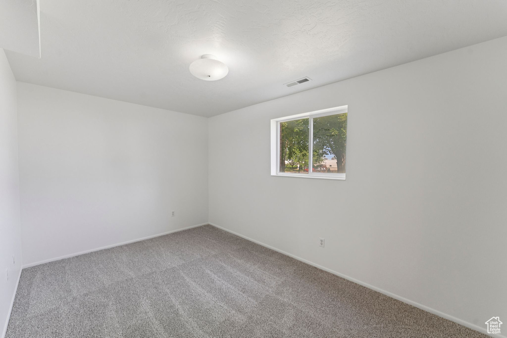 Carpeted spare room featuring baseboards
