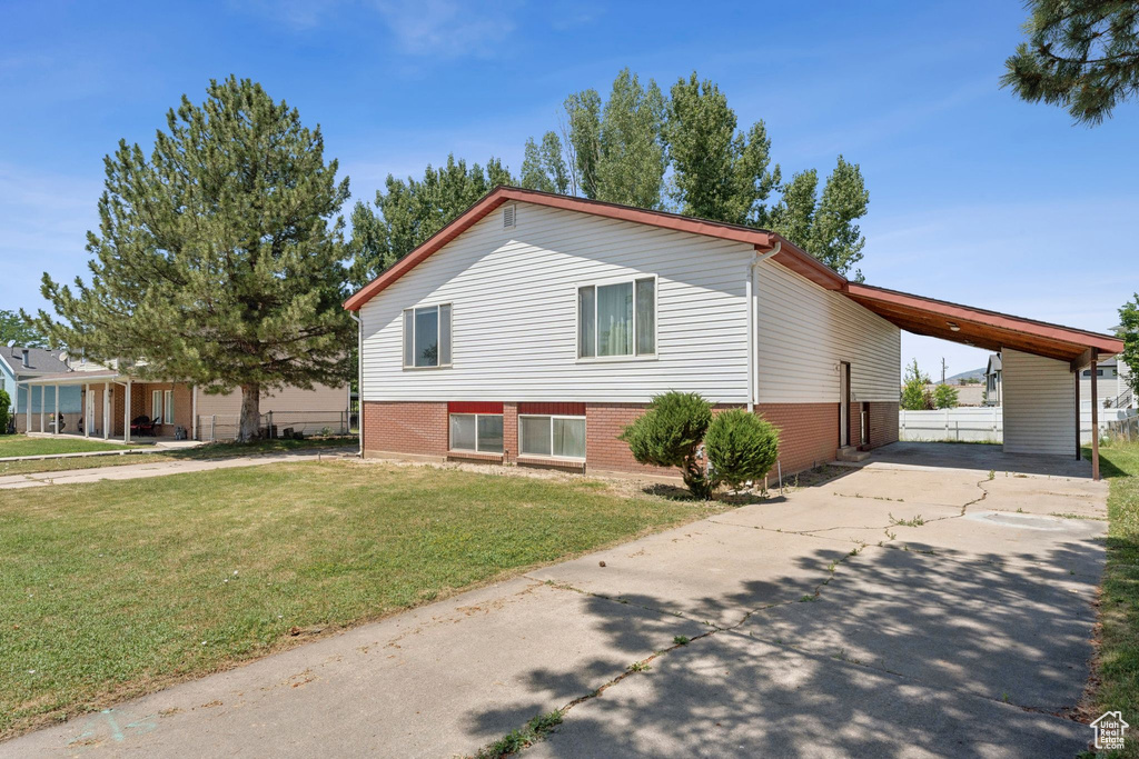 View of front of property featuring driveway, a carport, a front lawn, and brick siding