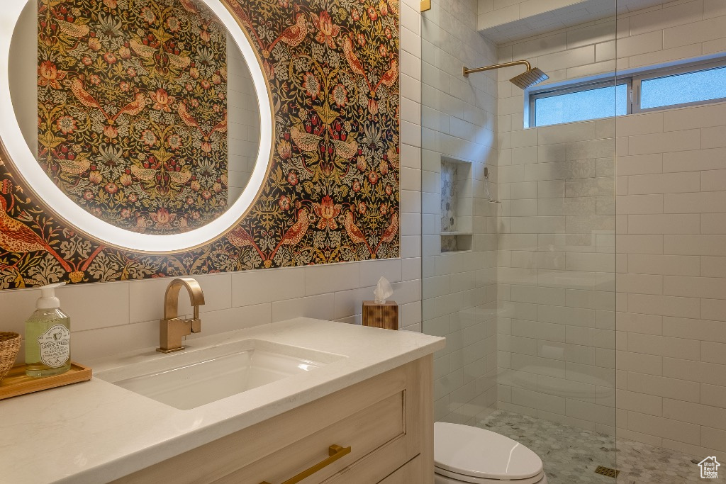 Bathroom featuring wallpapered walls, a walk in shower, vanity, a wainscoted wall, and tile walls