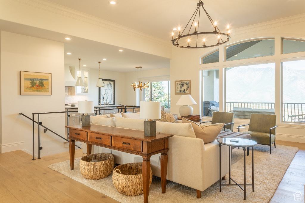 Living area featuring a chandelier, crown molding, light wood-style floors, and recessed lighting