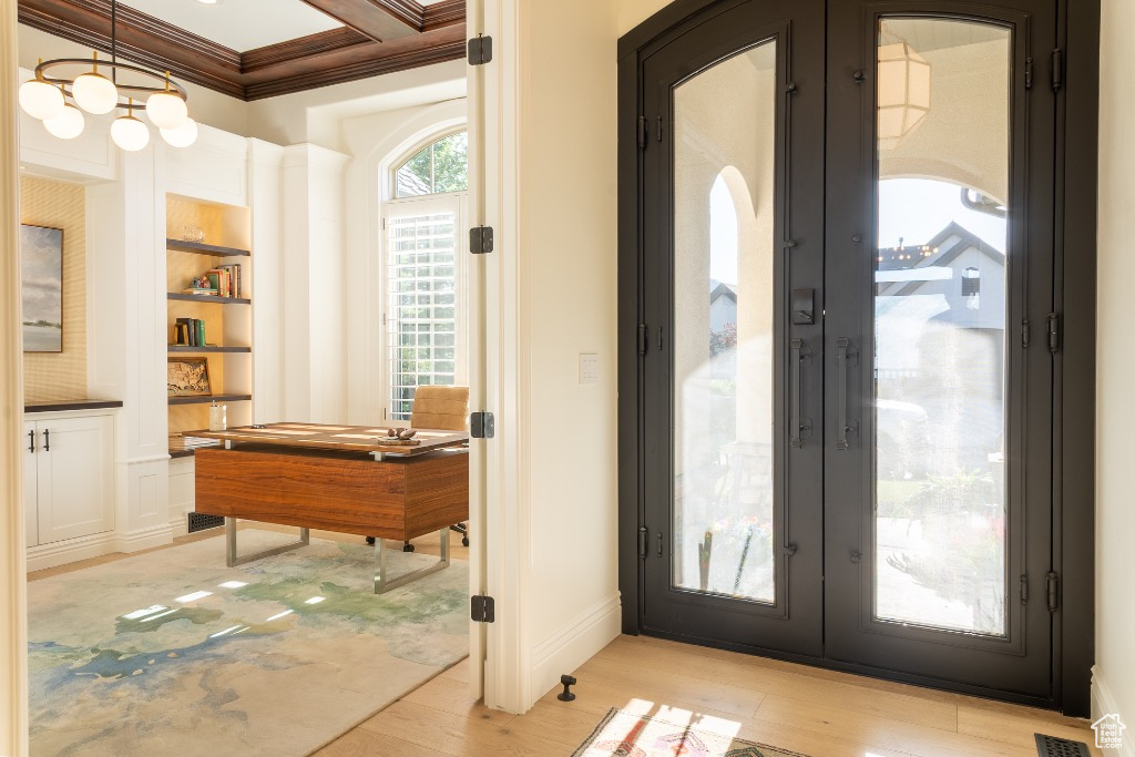 Foyer with french doors, ornamental molding, light wood finished floors, and arched walkways