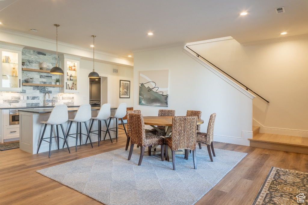 Dining space featuring crown molding, light wood-style floors, and recessed lighting
