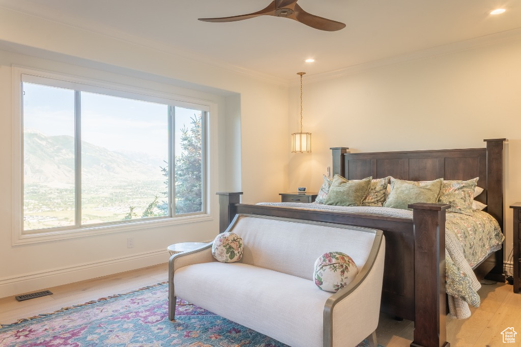 Bedroom featuring wood finished floors, ornamental molding, recessed lighting, a ceiling fan, and a mountain view