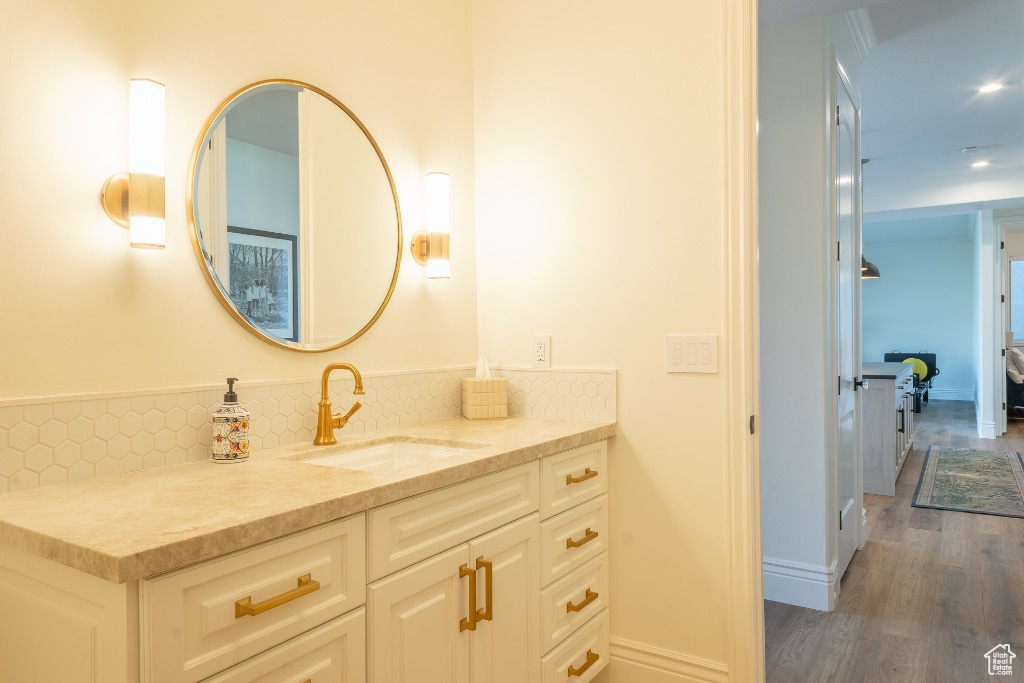 Bathroom featuring vanity, wood finished floors, decorative backsplash, and recessed lighting