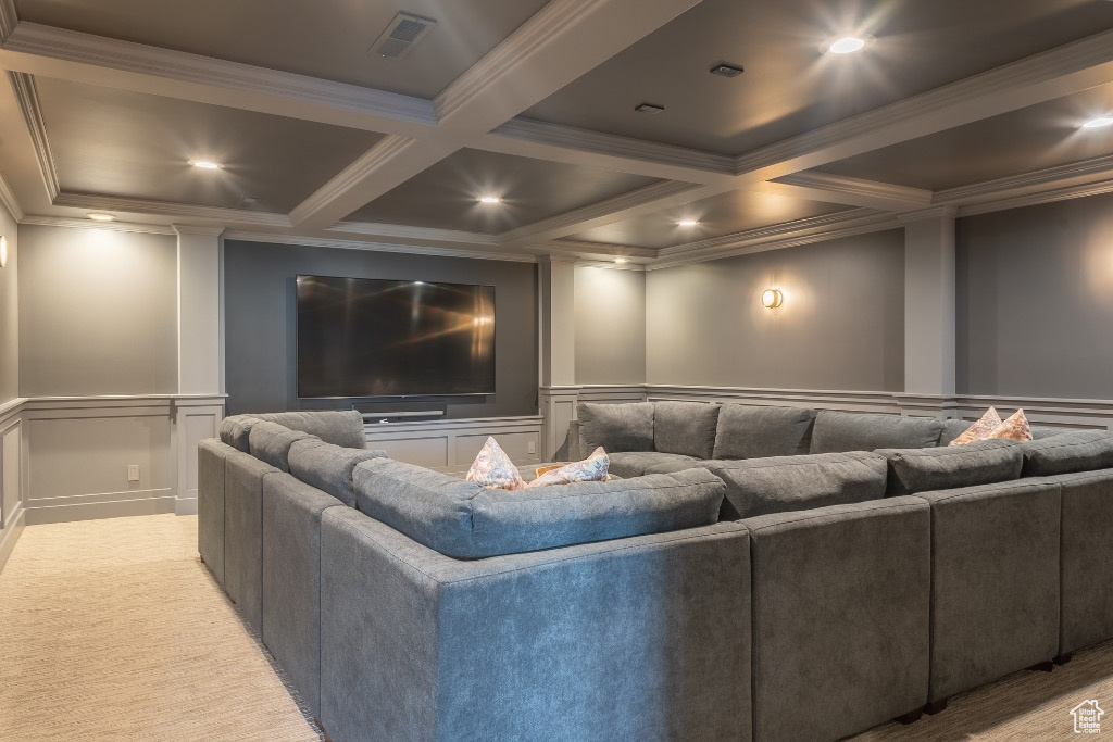 Carpeted home theater with coffered ceiling, a decorative wall, ornamental molding, and beam ceiling