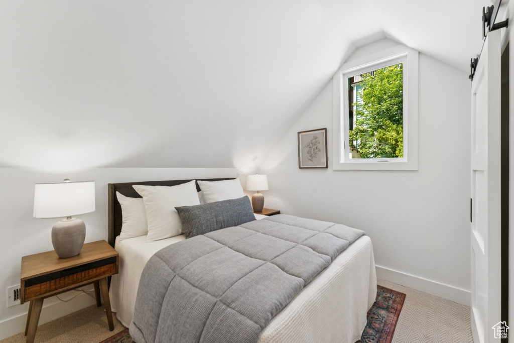 Carpeted bedroom featuring vaulted ceiling and baseboards