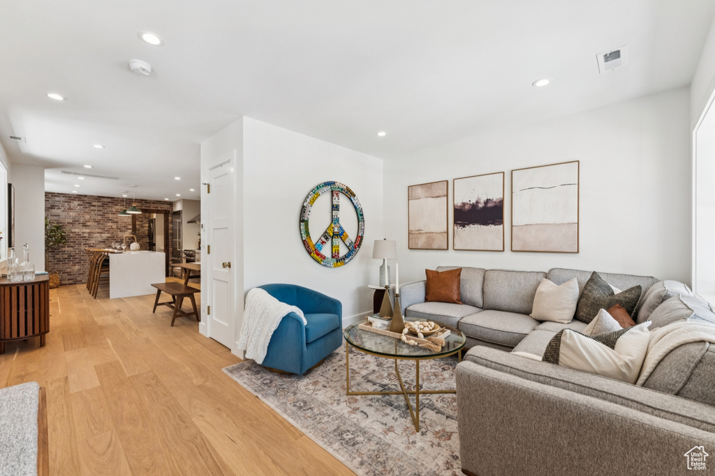 Living room with light wood-type flooring, recessed lighting, and brick wall