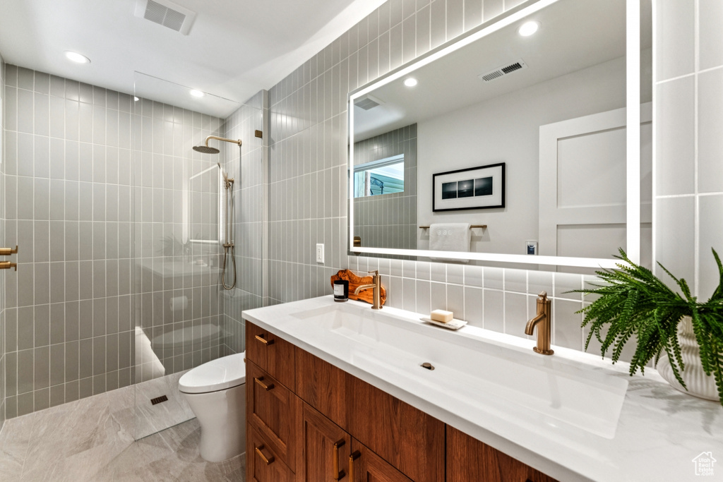 Full bath with tile walls, vanity, a walk in shower, and recessed lighting