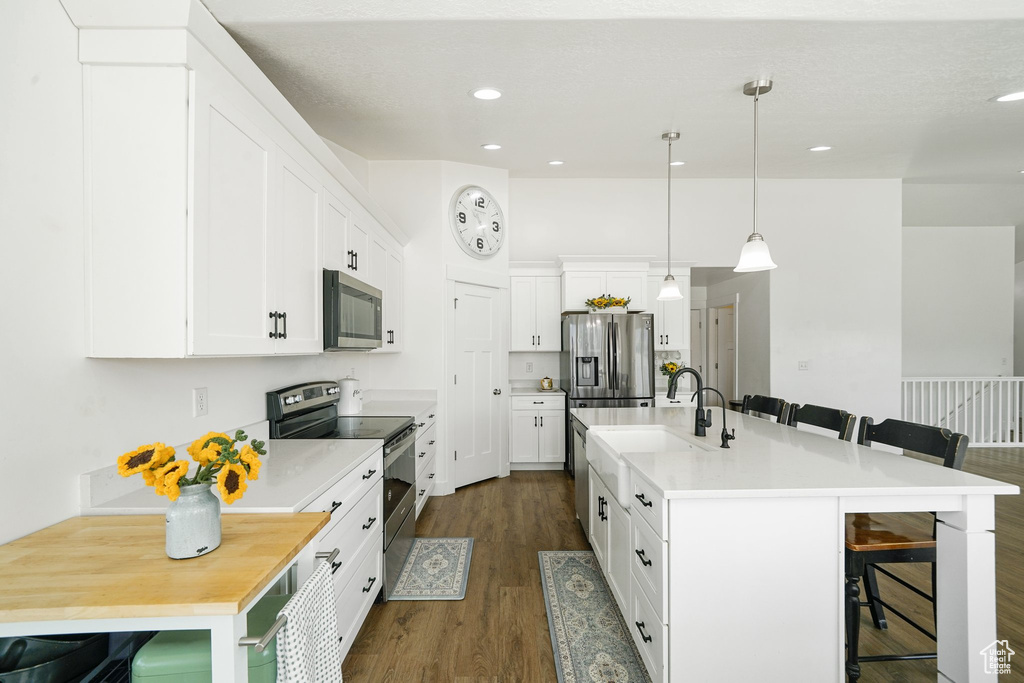 Kitchen featuring stainless steel appliances, a breakfast bar, dark wood-type flooring, white cabinetry, and recessed lighting