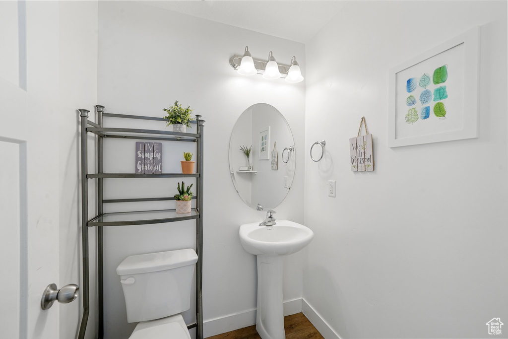 Half bathroom featuring toilet and wood finished floors