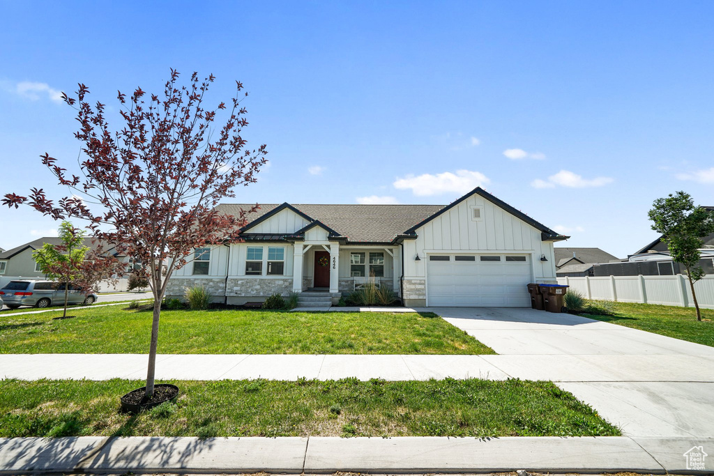 View of front of property with board and batten siding, an attached garage, and driveway