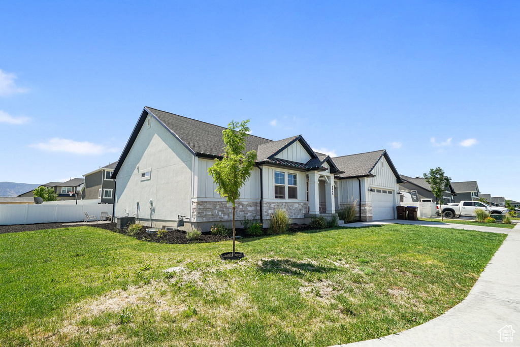 View of front of house with board and batten siding, concrete driveway, an attached garage, stone siding, and a shingled roof