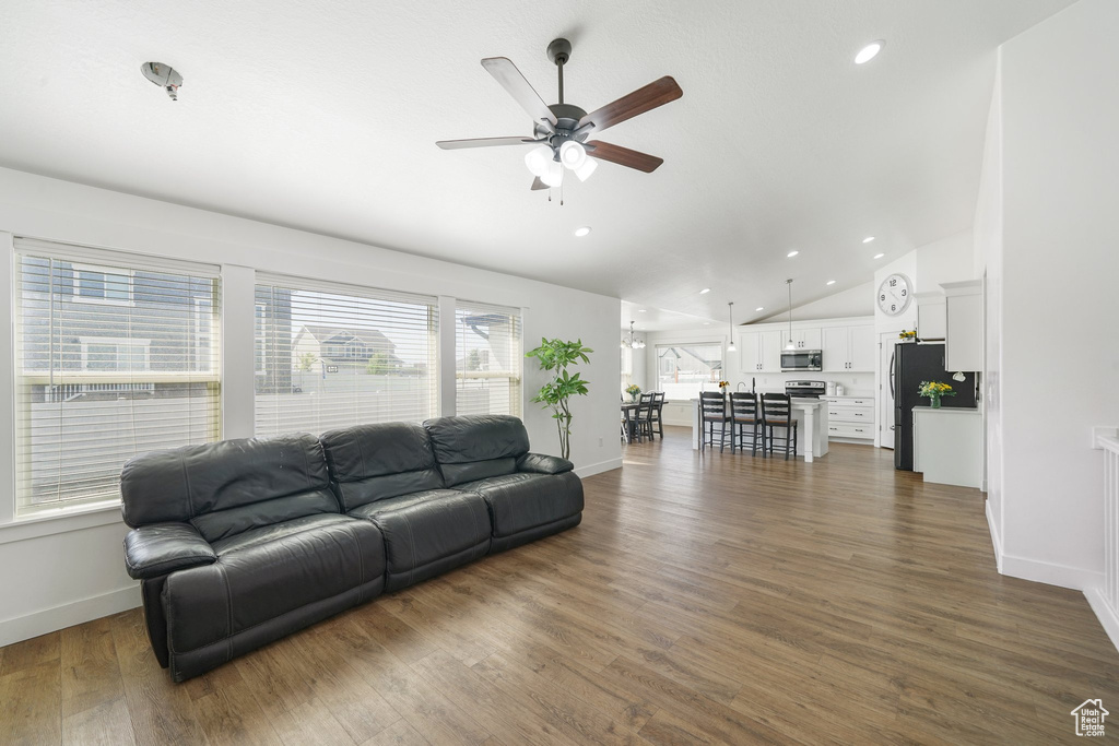 Living room with a ceiling fan, vaulted ceiling, dark wood-style flooring, and recessed lighting