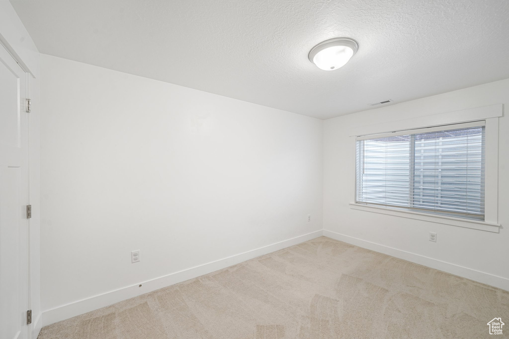 Spare room featuring a textured ceiling and light carpet
