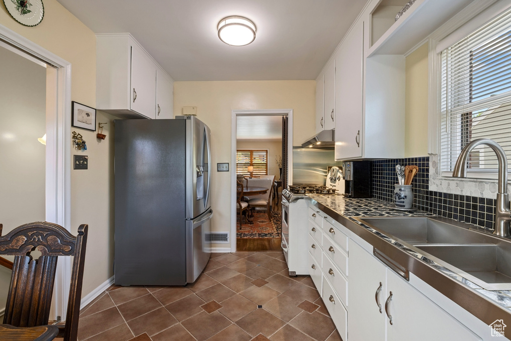 Kitchen featuring stainless steel appliances, plenty of natural light, white cabinets, and under cabinet range hood