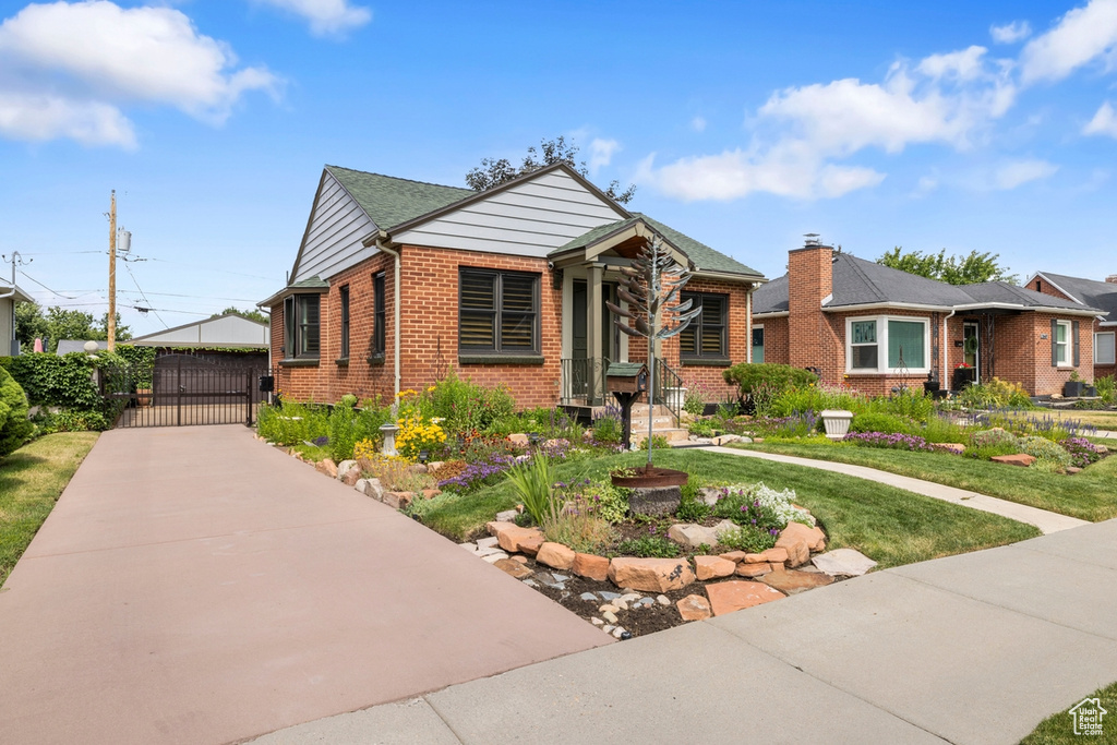 View of front of home with a gate, brick siding, and a front lawn