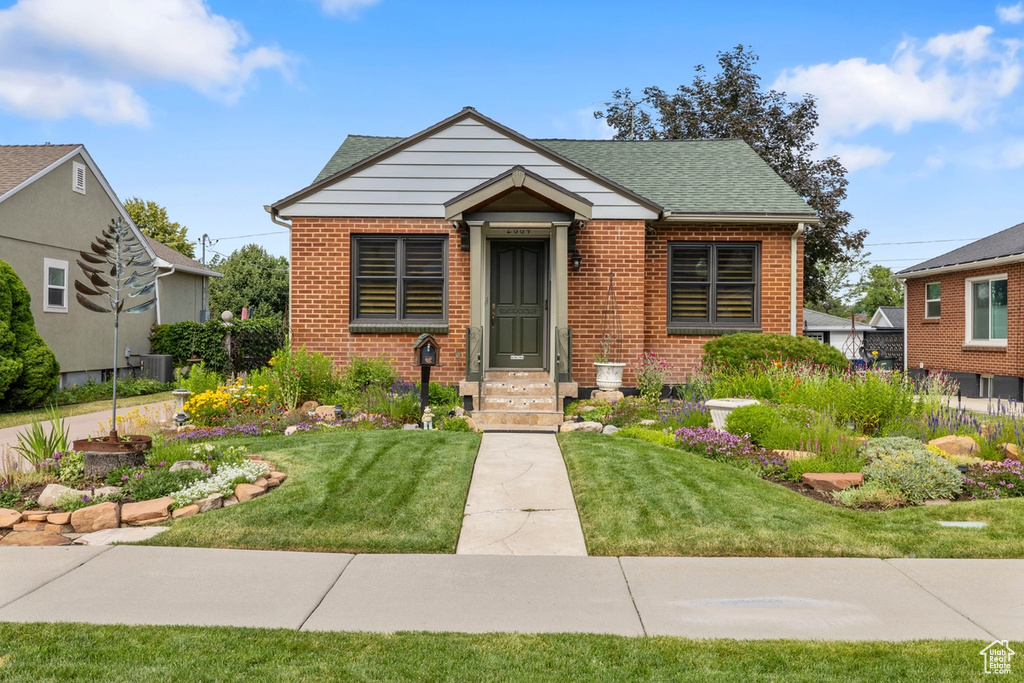 Bungalow-style home with brick siding, a front lawn, and a shingled roof