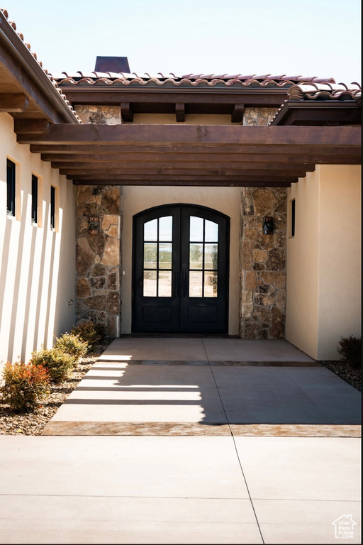 Property entrance with french doors, stone siding, and stucco siding