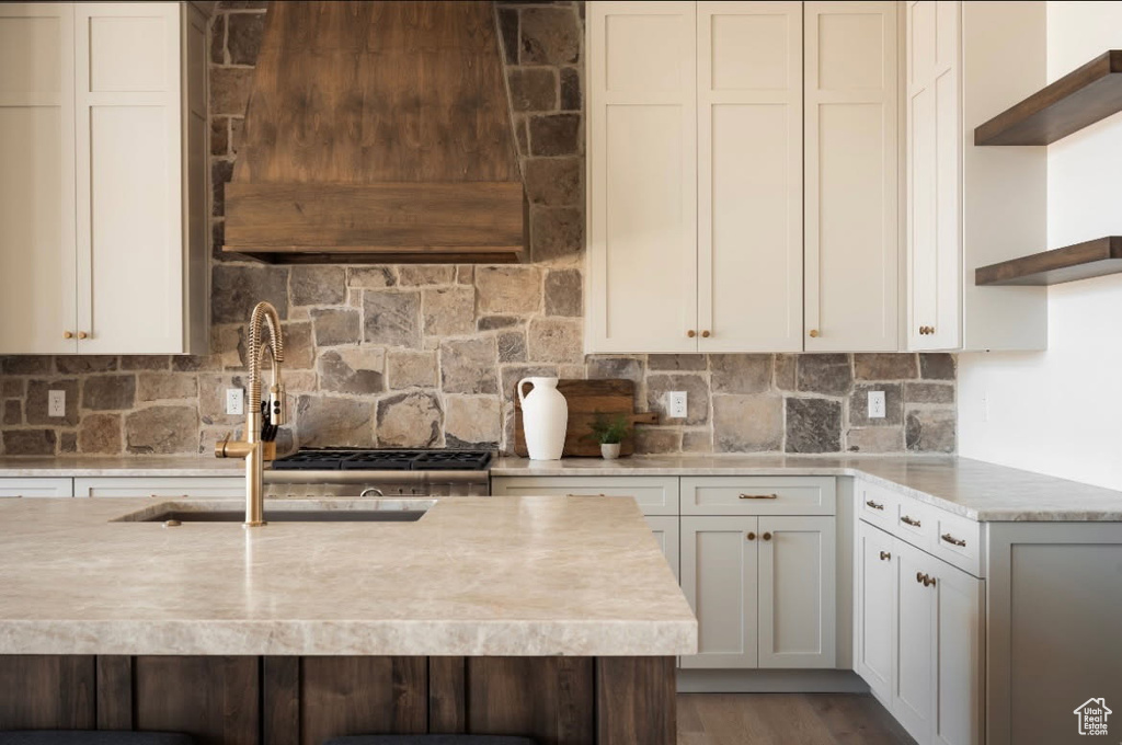 Kitchen with open shelves, ventilation hood, light countertops, and backsplash