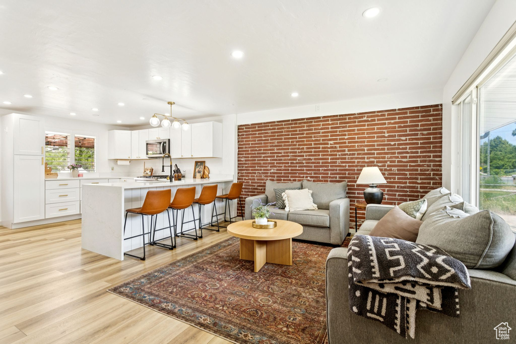 Living room featuring brick wall, light wood finished floors, and recessed lighting