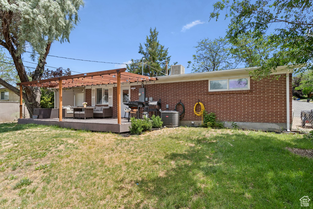 Back of property with an outdoor hangout area, brick siding, a wooden deck, a chimney, and a pergola