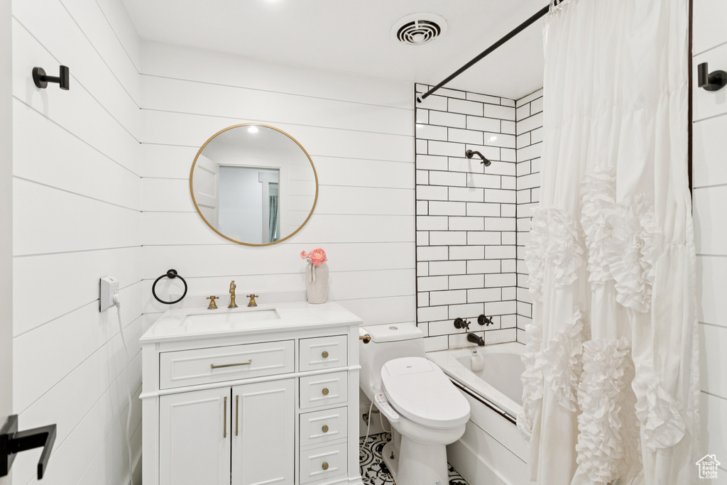 Full bath featuring shower / bath combo, vanity, and tile walls