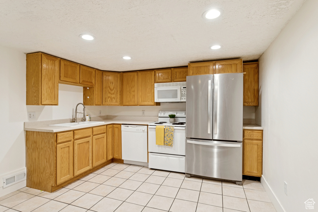 Kitchen with white appliances, light tile patterned floors, light countertops, and recessed lighting