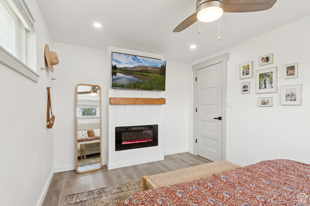 Bedroom with wood finished floors, a large fireplace, recessed lighting, and ceiling fan