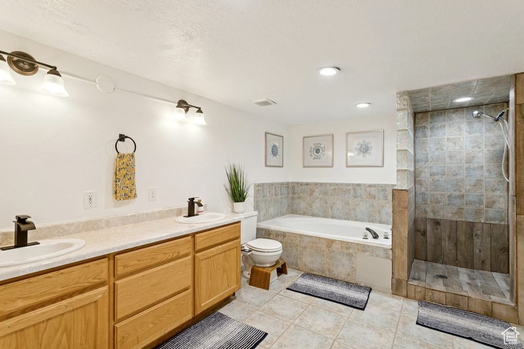 Bathroom featuring a garden tub, tiled shower, tile patterned floors, and double vanity