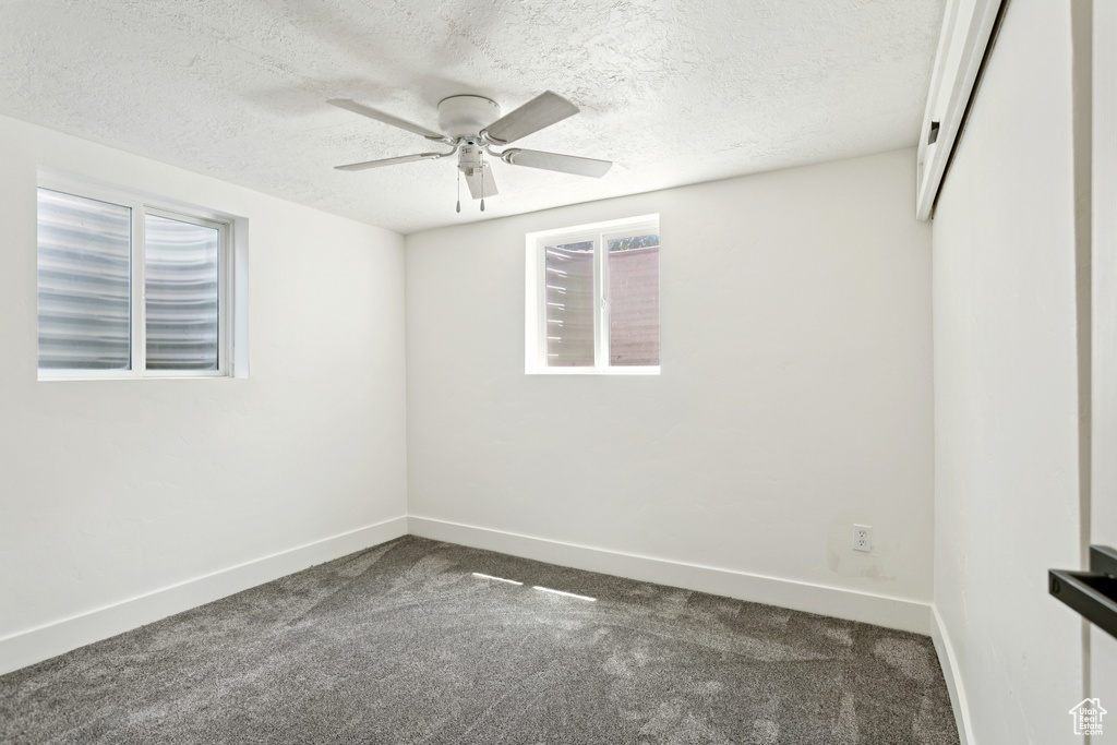 Carpeted spare room featuring a textured ceiling and a ceiling fan
