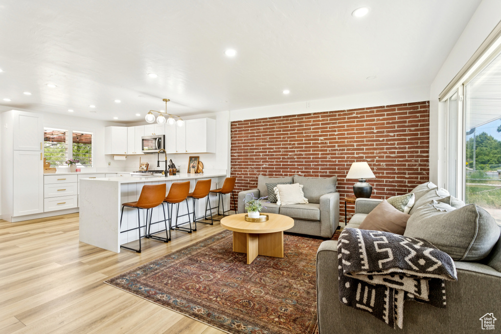 Living room featuring brick wall, light wood finished floors, and recessed lighting