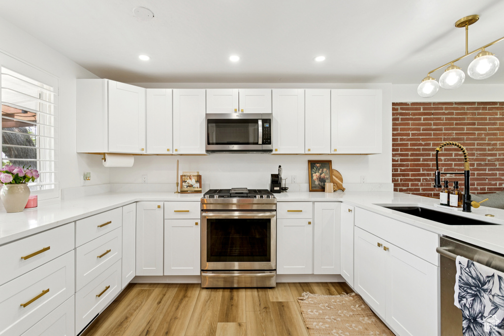 Kitchen featuring stainless steel appliances, white cabinets, light wood finished floors, light countertops, and recessed lighting