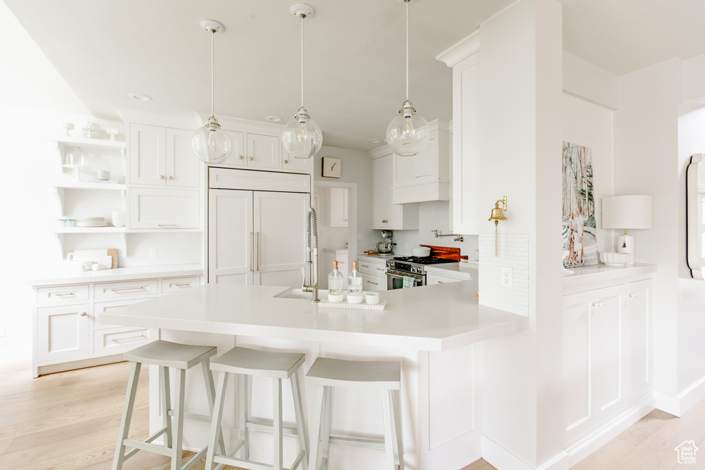 Kitchen with paneled built in refrigerator, gas range, white cabinetry, and a kitchen breakfast bar