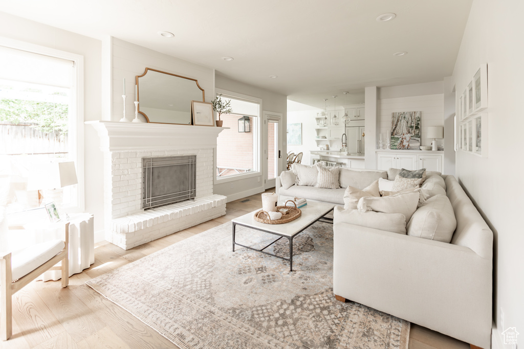 Living room with wood finished floors, a brick fireplace, and recessed lighting