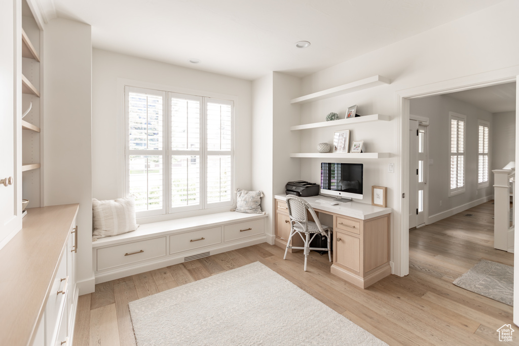 Office area featuring light wood finished floors and built in desk
