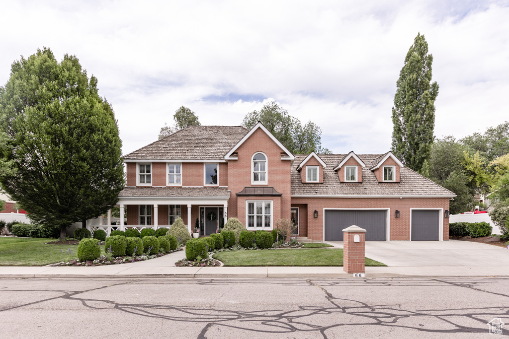 Traditional home with brick siding, concrete driveway, an attached garage, and a front yard
