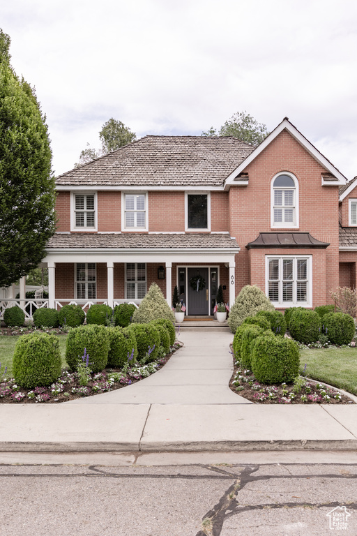 Traditional home featuring covered porch and brick siding