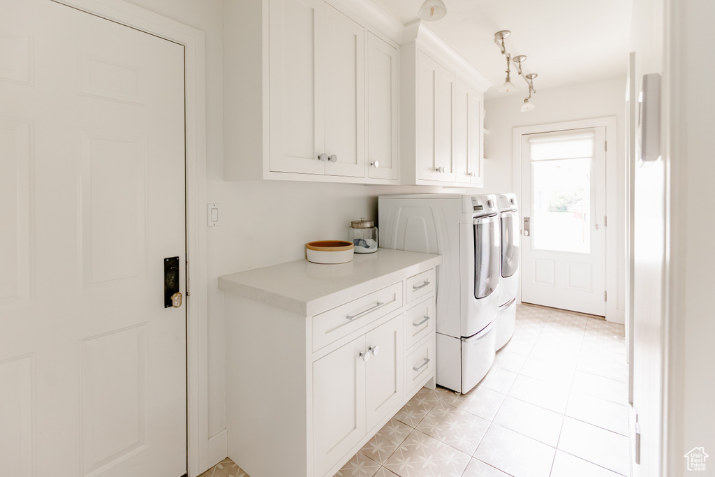 Laundry area featuring washer and dryer, cabinet space, and light tile patterned floors