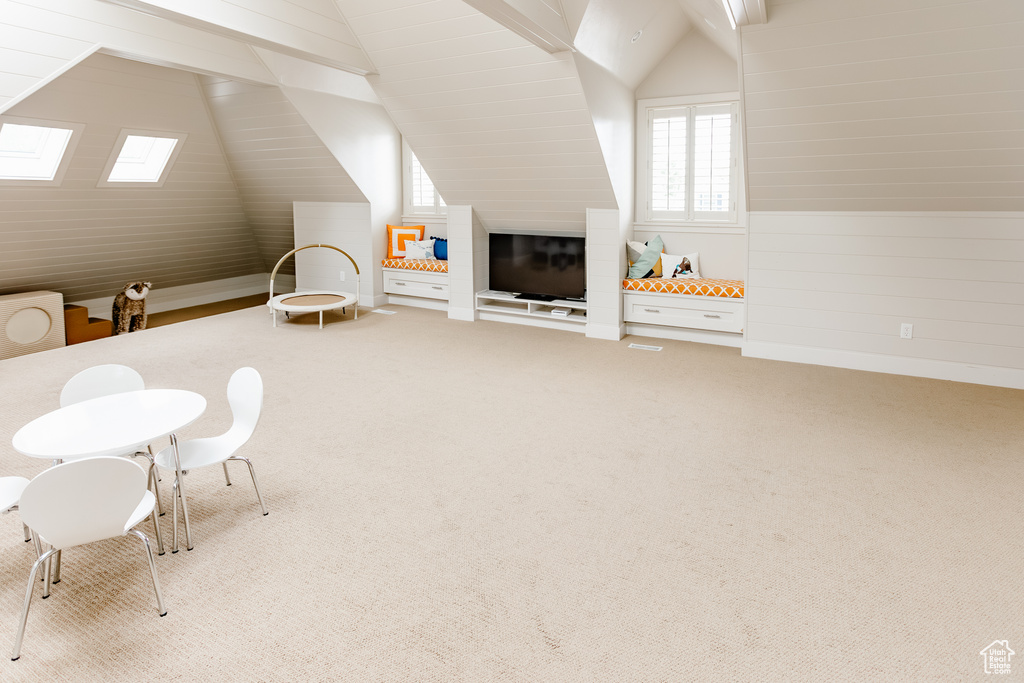 Additional living space with carpet flooring, vaulted ceiling, and wood walls