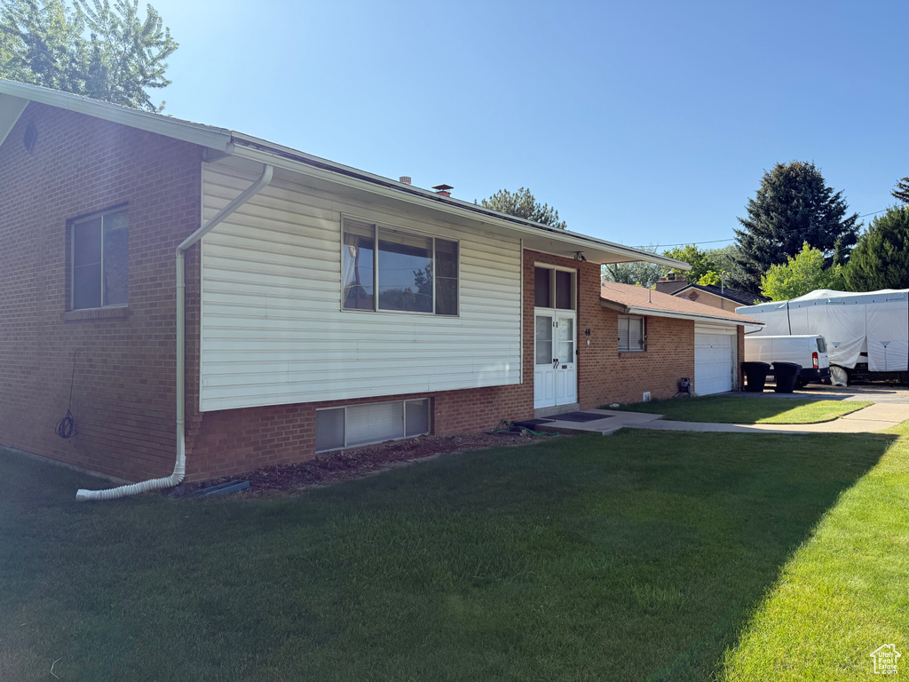 Split level home with a front lawn, a garage, and concrete driveway
