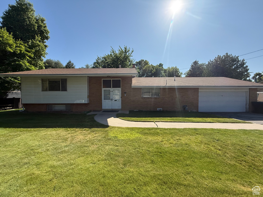View of front of house with concrete driveway, an attached garage, a front lawn, brick siding, and french doors
